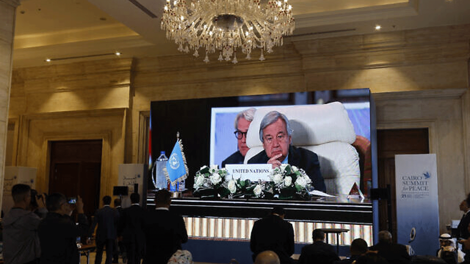 الصحفيون يشاهدون شاشة كبيرة تظهر الأمين العام للأمم المتحدة أنطونيو غوتيريش في القمة الدولية للسلام التي استضافها الرئيس المصري في القاهرة في 21 أكتوبر\تشرين الأول 2023