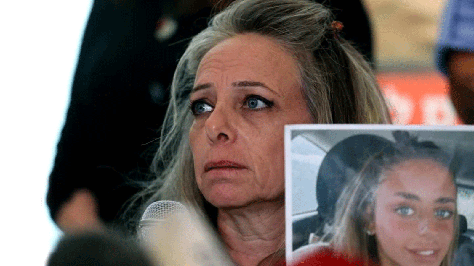 كيرين شيم، والدة المرأة الإسرائيلية الفرنسية ميا شيم، المحتجزة كرهينة من قبل مسلحي حماس في غزة، تحمل صورة لابنتها بينما تتحدث إلى الصحافة في تل أبيب في 17 أكتوبر 2023، وسط المعارك المستمرة بين إسرائيل وحماس