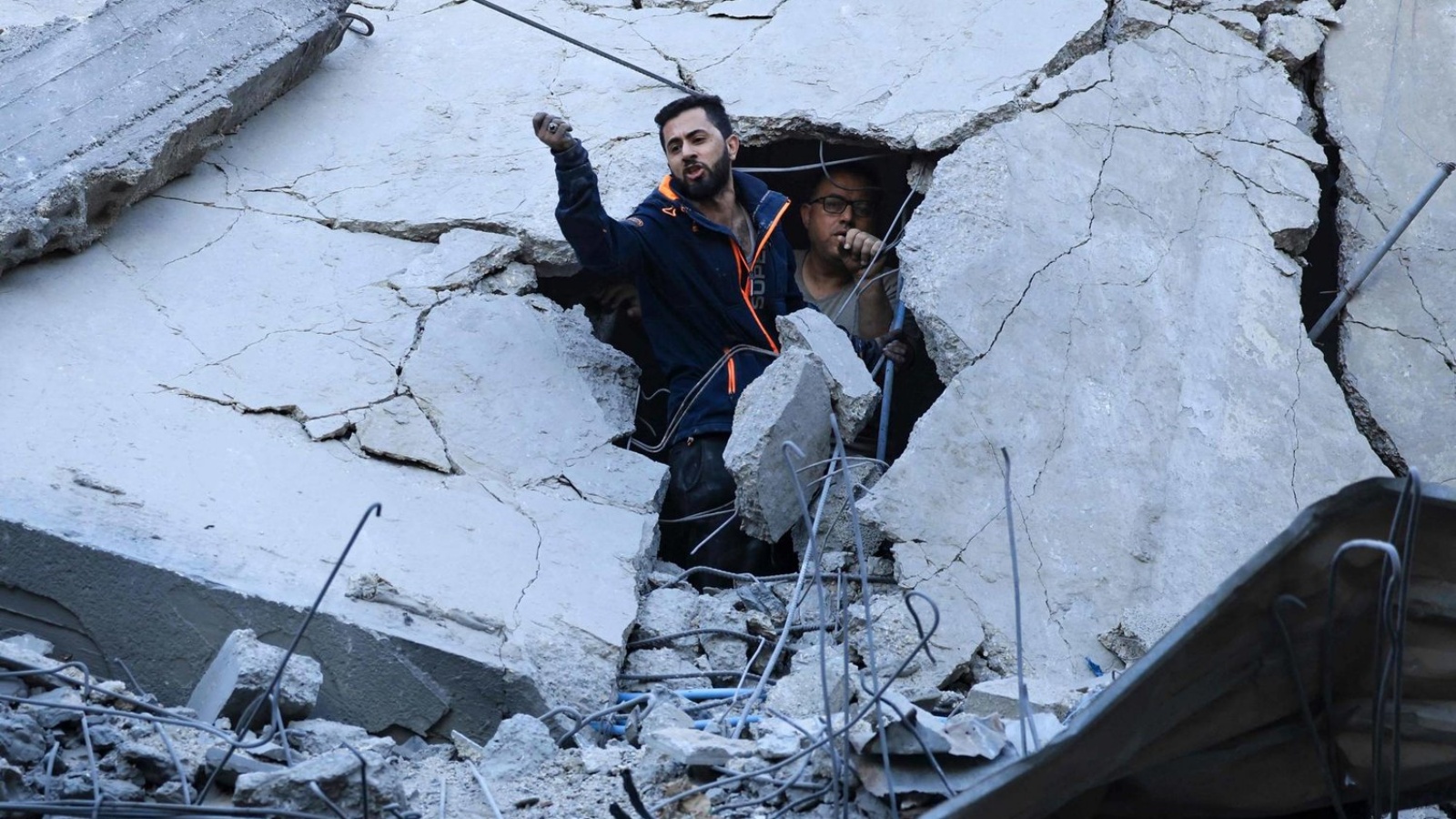 عضوان في الدفاع المدني الفلسطيني يبحثان عن ناجين بين أنقاض مبنى أصيب أثناء القصف الإسرائيلي في خان يونس بجنوب قطاع غزة 