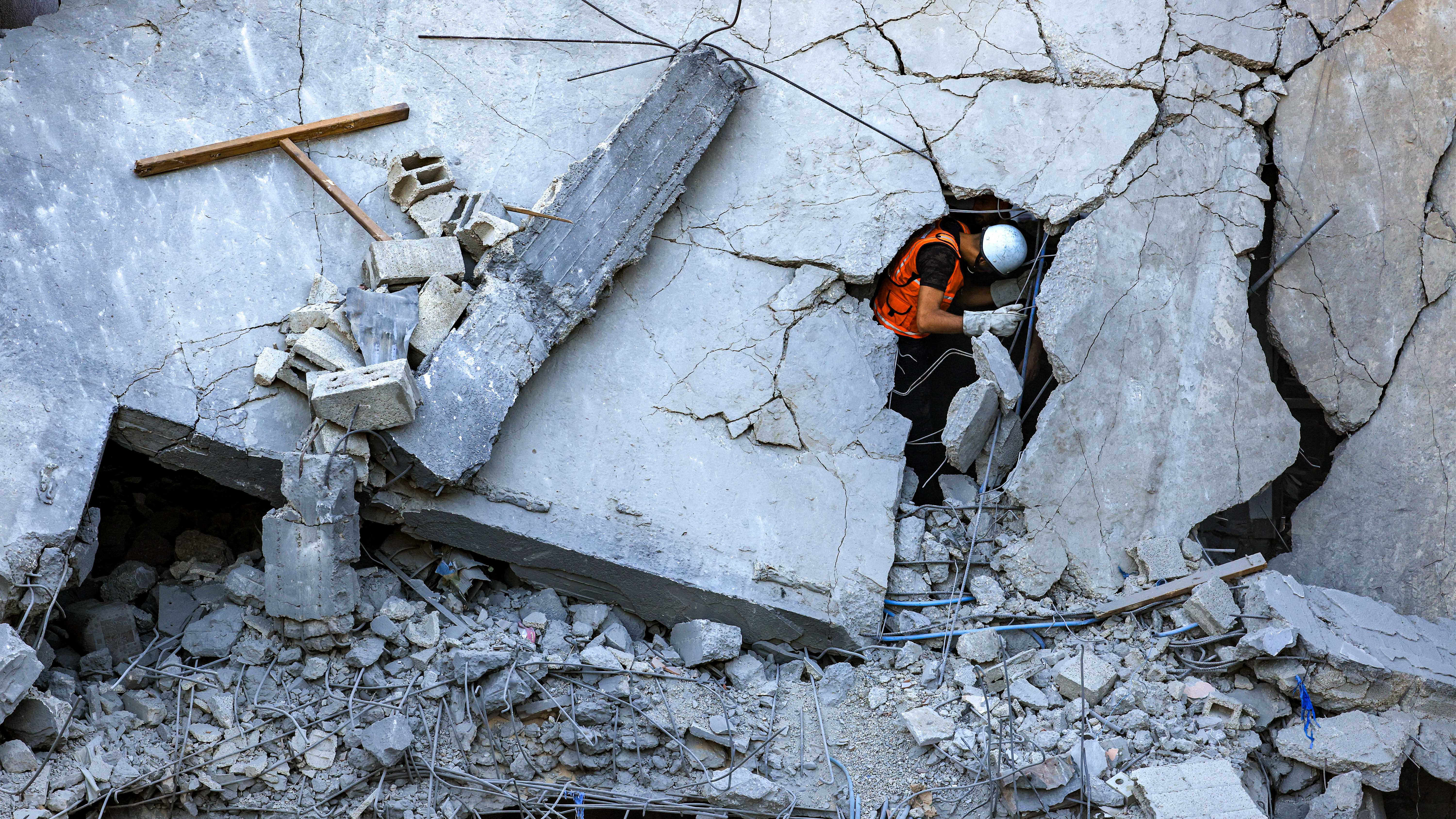 عنصر في الدفاع المدني الفلسطيني في خان يونس يمر من خلال شقّ في مبنى انهار نتيجة القصف الإسرائيلي. (أ ف ب)