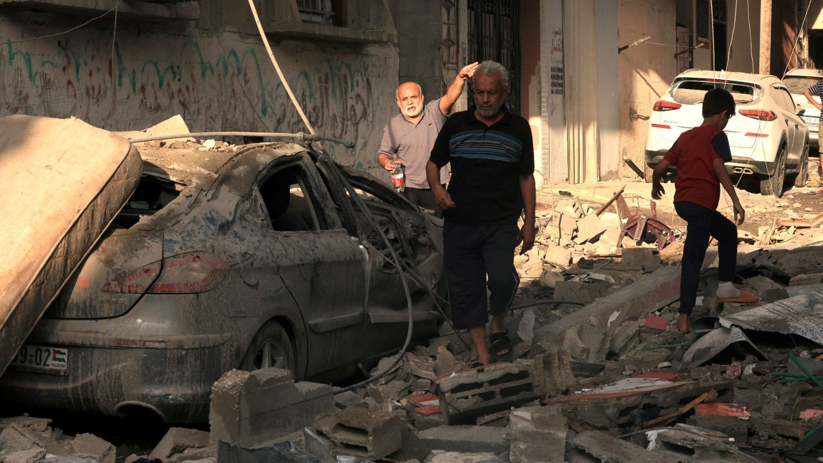 رجال فلسطينيون يمرون وسط أنقاض في خان يونس جنوب قطاع غزة عقب قصف اسرائيلي 27 أكتوبر 2023