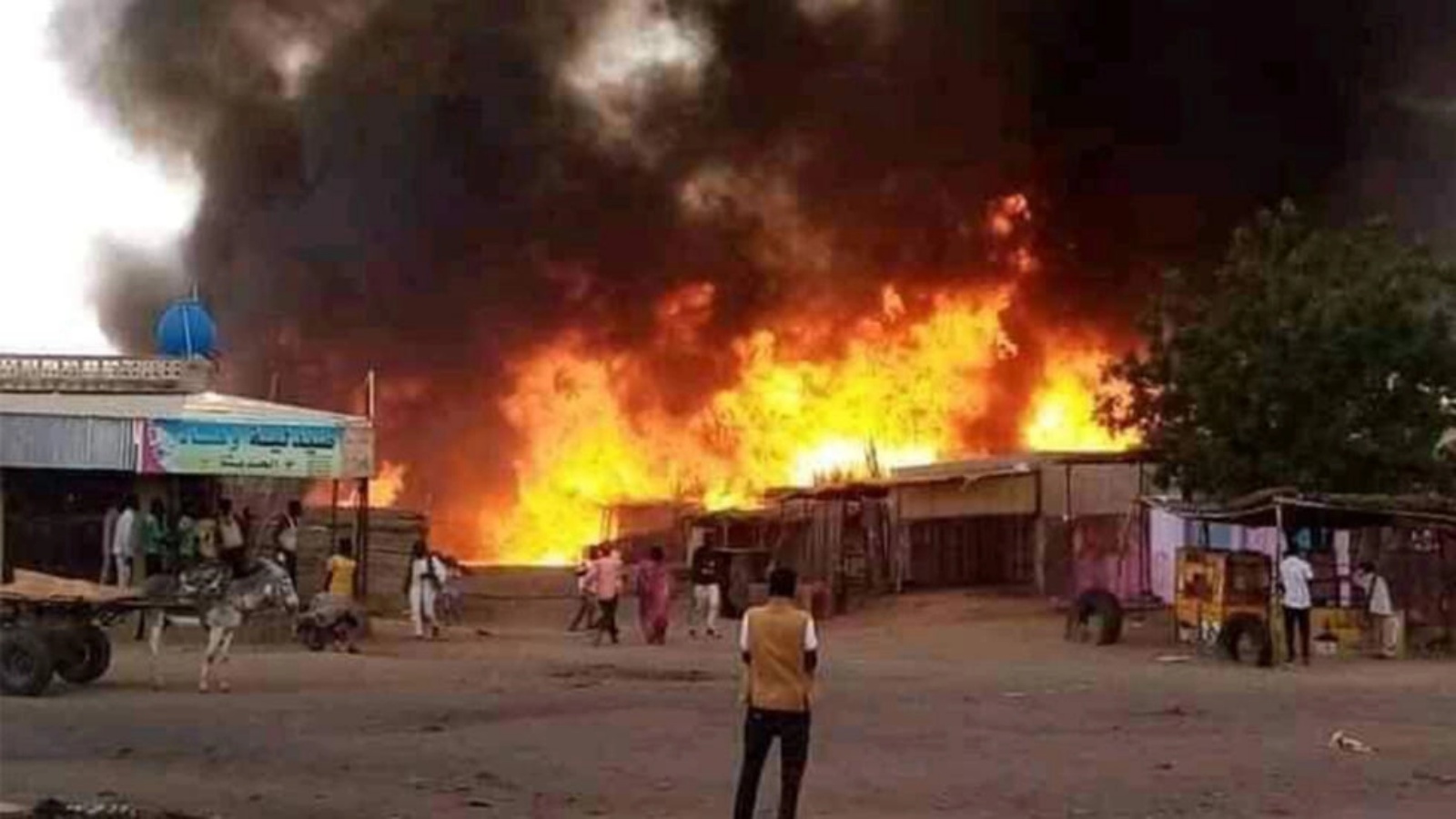 رجل يقف متفرجا بينما تشتعل النيران في منطقة سوق للماشية في الفاشر عاصمة ولاية شمال دارفور السودانية في 1 سبتمبر 2023 في أعقاب قصف لقوات الدعم السريع 