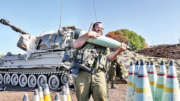 جندي إسرائيلي يحمل قذيفة أميركية الصنع من عيار 155 ملم 