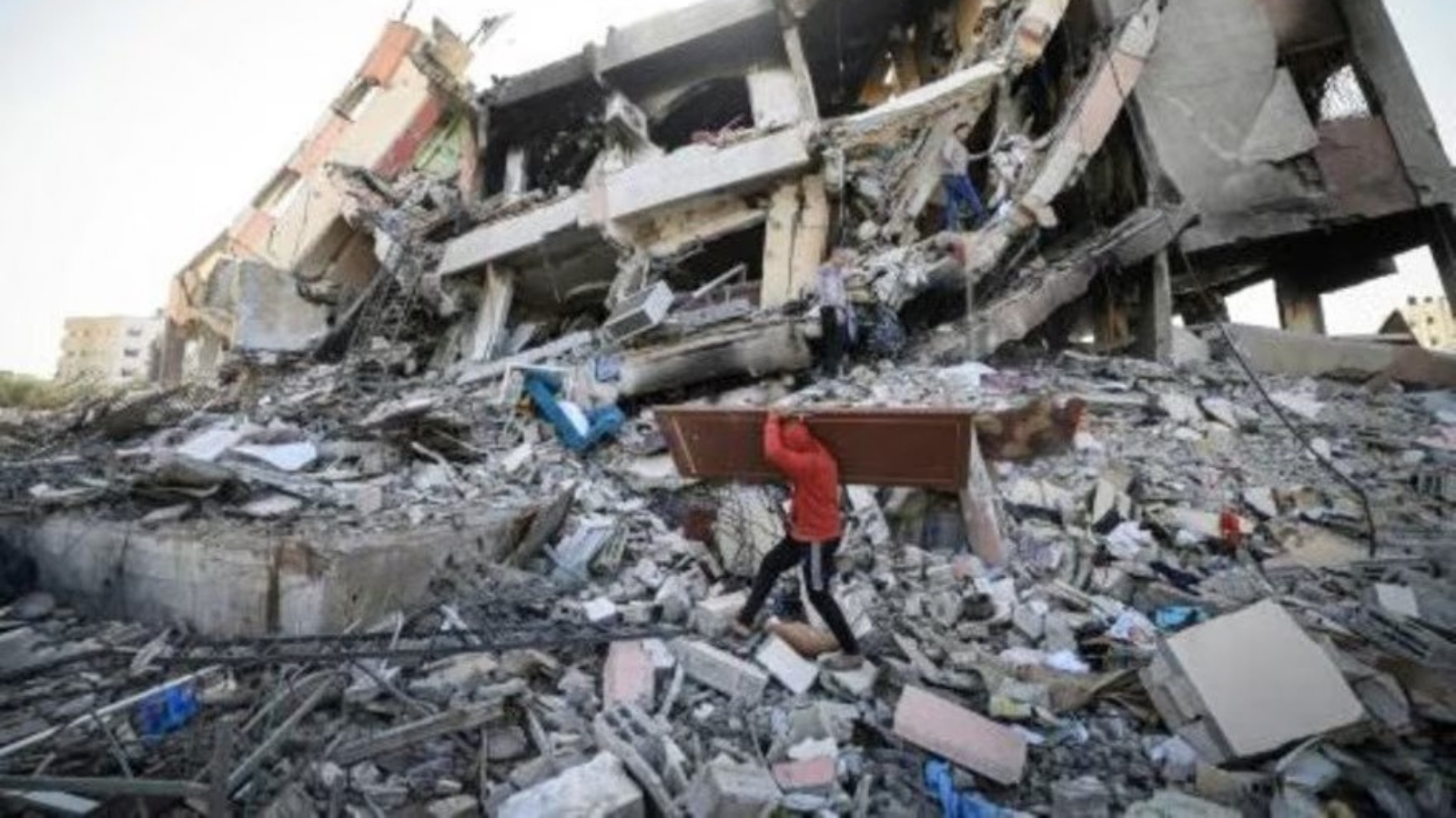 فلسطينيون يحملون بعض مقتنياتهم يسيرون وسط أنقاض المباني المدمرة في حيّ الزهراء بالضواحي الجنوبية لمدينة غزة في 26 نوفمبر 2023 مع دخول الهدنة بين إسرائيل وحماس يومها الثالث
