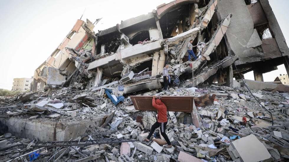 فلسطينيون يحملون بعض مقتنياتهم يسيرون وسط أنقاض المباني المدمرة في حيّ الزهراء بالضواحي الجنوبية لمدينة غزة في 26 تشرين الثاني/نوفمبر 2023 مع دخول الهدنة بين إسرائيل وحماس يومها الثالث