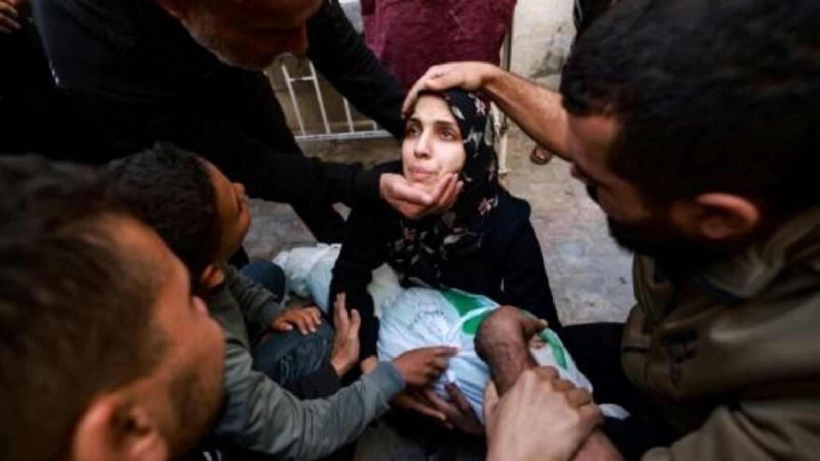  أقارب يحاولون تهدئة امرأة تحتضن جثمان طفلتها التي قتلت في ضربة إسرائيلية في رفح، في باحة مستشفى النجار في الأول من ديسمبر 2023