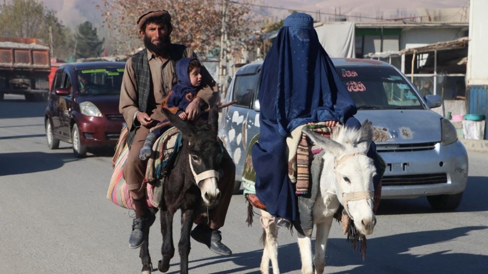 رجل أفغاني مع امرأة ترتدي البرقع يركبان حمارين على طريق في منطقة فايز آباد بمقاطعة بدخشان 28 نوفمبر 2023