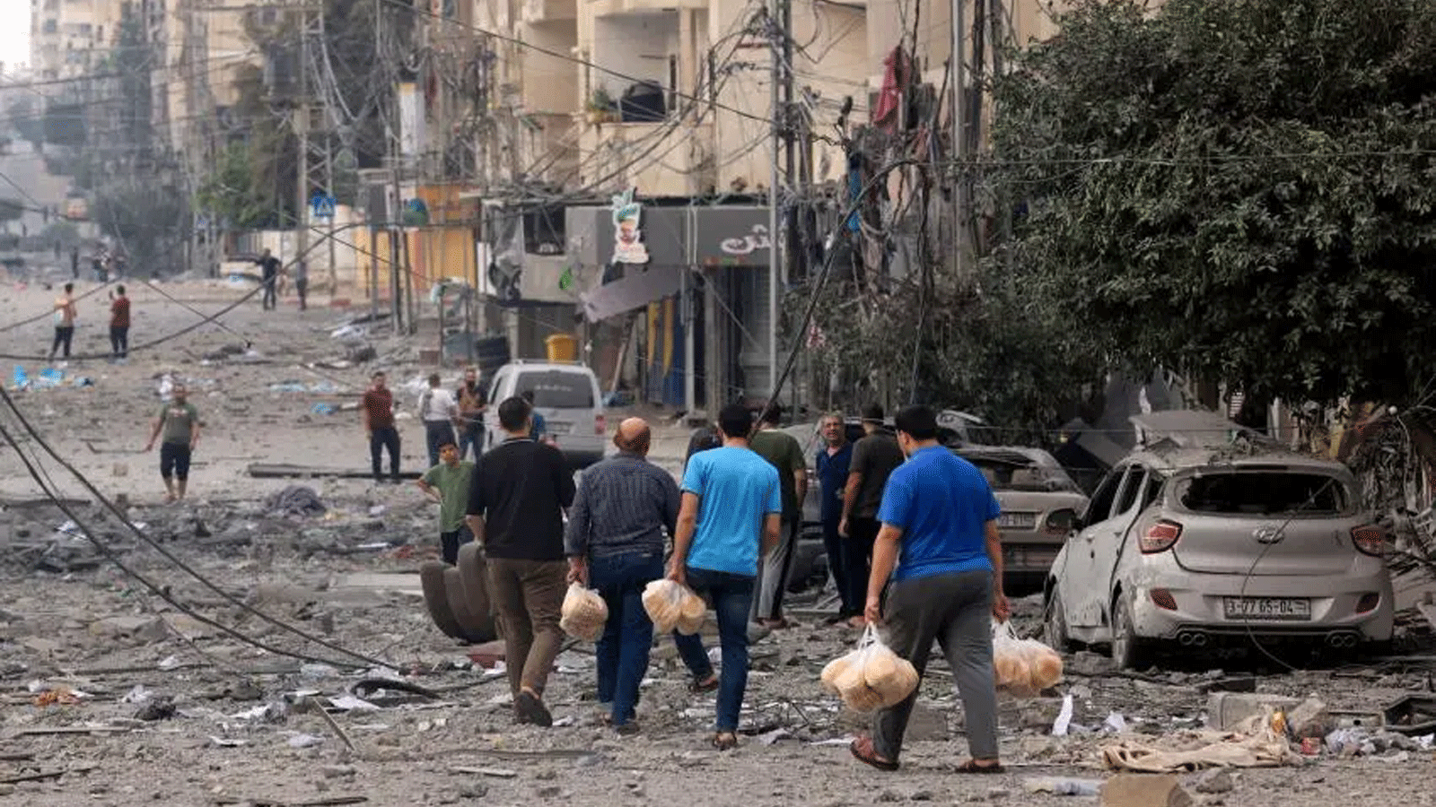 رجال فلسطينيون يحملون الخبز في شارع تعرّض لقصف شديد في أعقاب الغارات الجوية الإسرائيلية على مدينة غزة