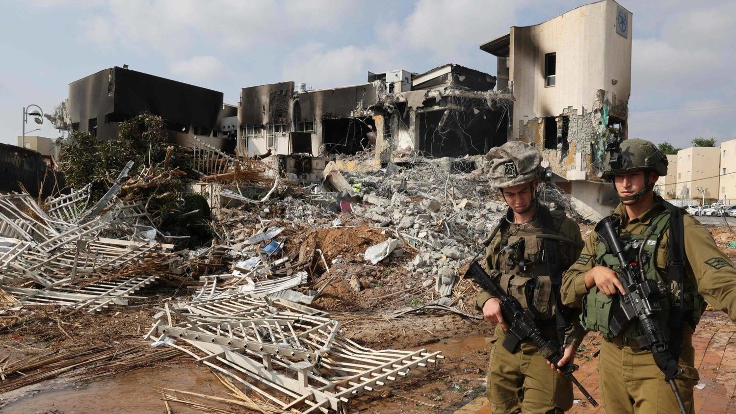 جنديان إسرائيليان يسيران أمام مركز للشرطة الإسرائيلية تضرر خلال المعارك لطرد مقاتلي حماس الذين تمركزوا في داخله، في 8 أكتوبر 2023