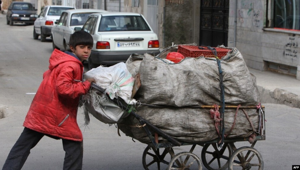 صورة أرشيفية لفتى إيراني يدفع عربة مليئة بالمواد القابلة لإعادة التدوير في جنوب طهران. أ ف ب 