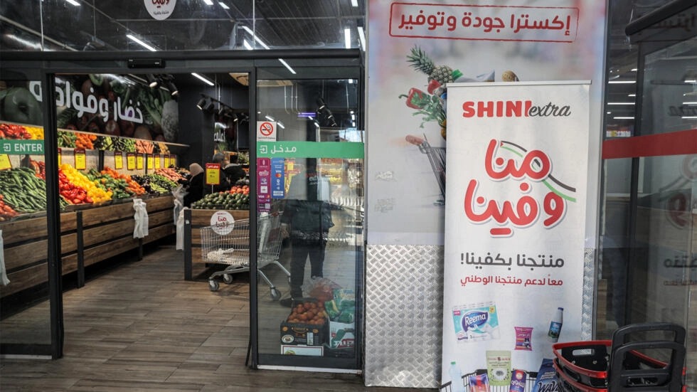 لافتة تحدد المنتجات المحلية عند مدخل سوبر ماركت في رام الله بالضفة الغربية المحتلة في 26 كانون الأول/ديسمبر 2023، كجزء من حملة أوسع تحث الفلسطينيين على مقاطعة المنتجات الإسرائيلية وشراء السلع المصنوعة محليا