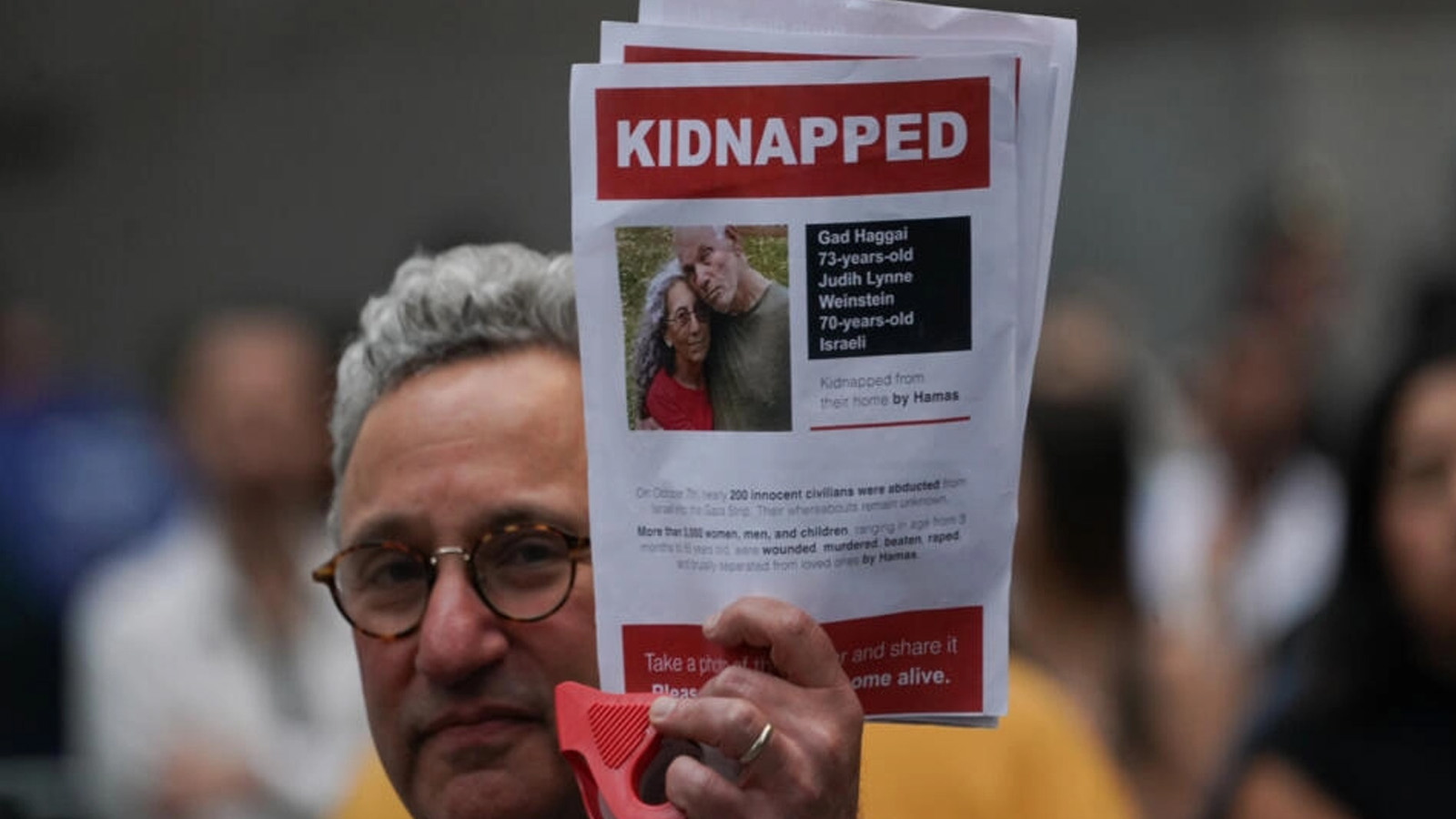 رجل يحمل صورة الرهينتين جاد وجوديث واينستاين حاغاي خلال مسيرة في نيويورك. 26 أكتوبر(تشرين الأول) 2023