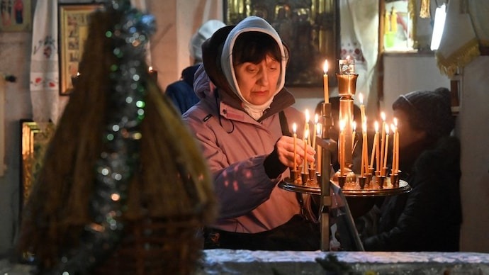 امرأة تضيء شمعة خلال قداس عيد الميلاد الأرثوذكسي في كنيسة القديس يوحنا اللاهوتي في خاركيف، أوكرانيا