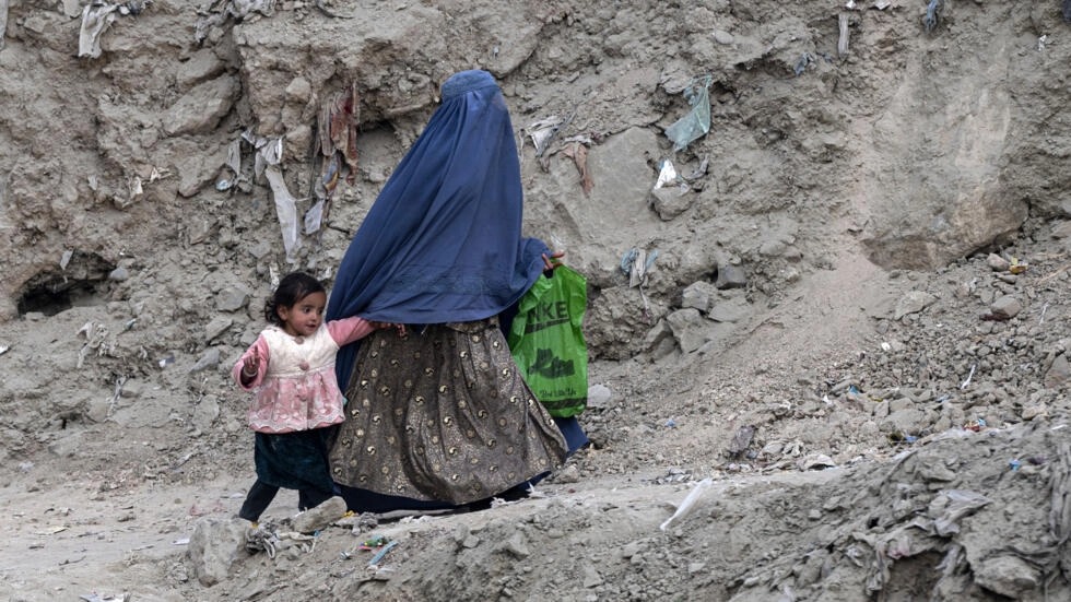 امرأة أفغانية ترتدي البرقع تسير مع فتاة على طول طريق في منطقة في كابول في 21 تشرين الثاني/نوفمبر 2023