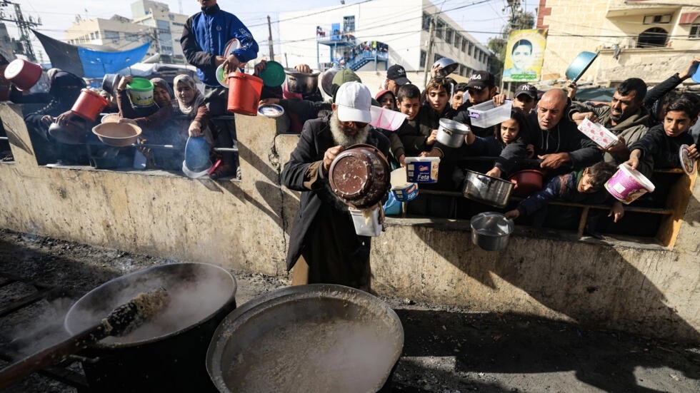 فلسطينيون يتسلمون وجبات طعام عند نقطة توزيع في مخيم رفح للاجئين في جنوب قطاع غزة في 23 كانون الأول/ديسمبر 2023