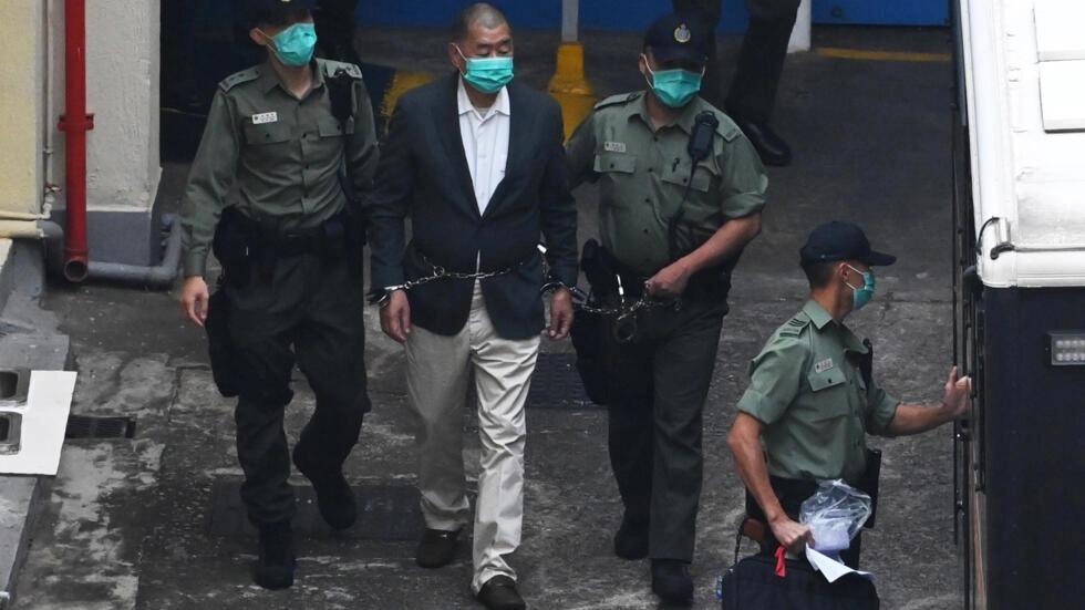 اقتياد قطب الإعلام المؤيد للديموقراطية في هونج كونج جيمي لاي إلى سيارة شرطة بينما كان يتجه إلى المحكمة لتوجيه الاتهام إليه بموجب قانون الأمن القومي الجديد المثير للجدل في 12 كانون الأول/ديسمبر 2020