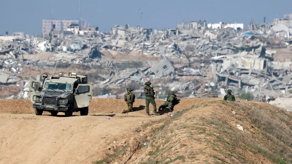 تظهر هذه الصورة الملتقطة من الحدود الإسرائيلية مع شمال قطاع غزة جنودًا إسرائيليين يراقبون مدينة غزة من موقع مطلّ في 1 يناير 2024