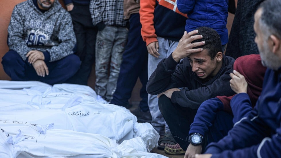 شاب يبكي أمام جثث أفراد من عائلتي صلاح وأبو حطب قتلوا عندما تعرضت الخيمة التي كانوا يحتمون بها للقصف الإسرائيلي، في مشرحة مركز ناصر الطبي في خان يونس في جنوب قطاع غزة، في 4 يناير 2024