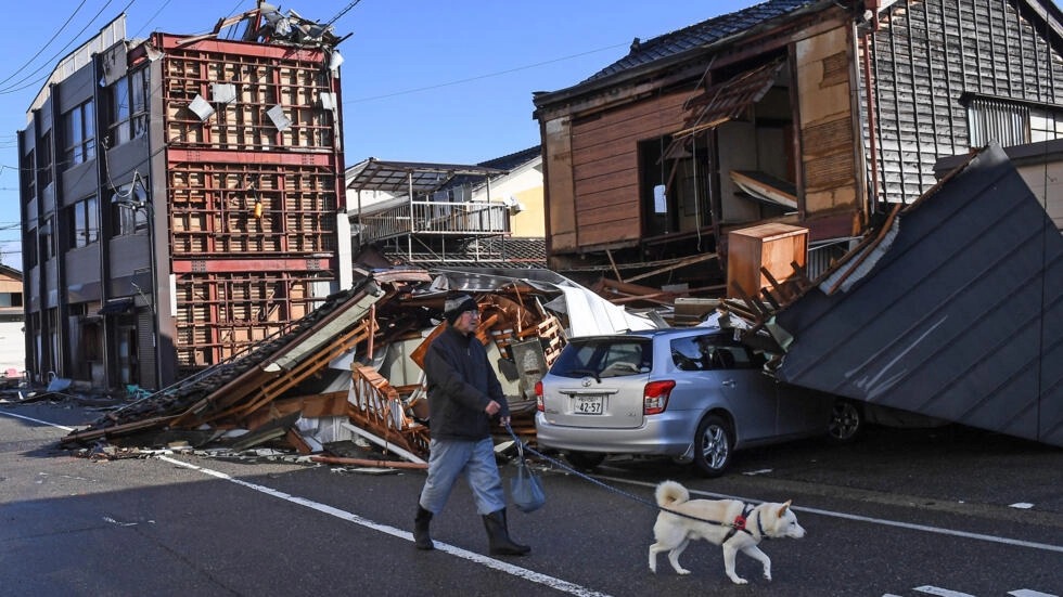 رجل يتنزه مع كلبه في اناميزو في مقاطعة ايشيكاوا في 4 كانون الثاني/يناير 2024 بعد زلزال رأس السنة