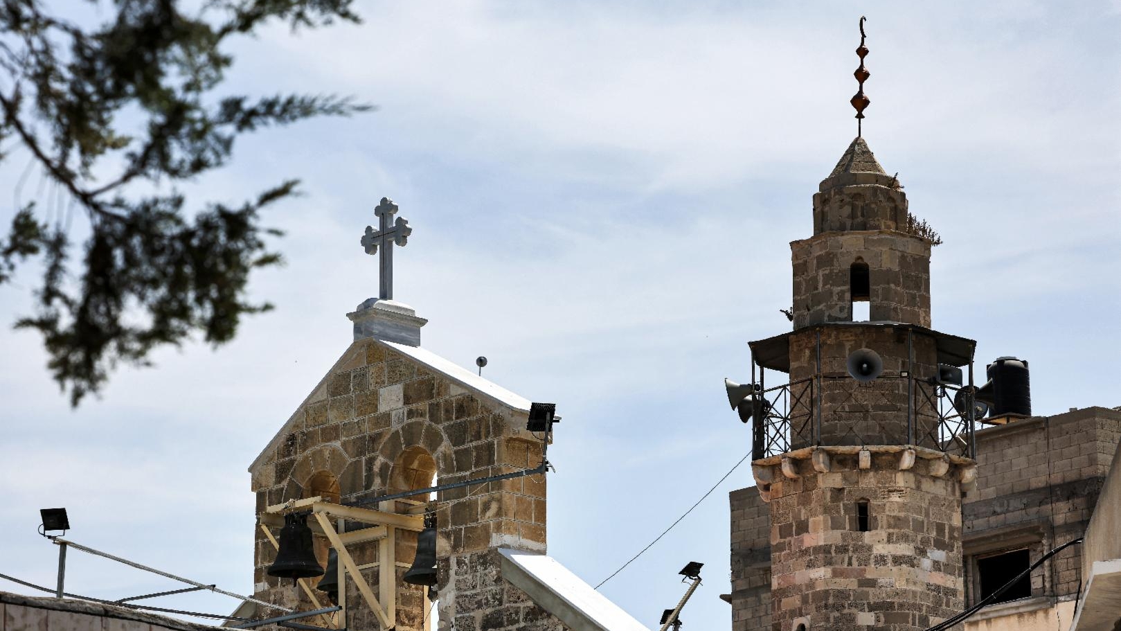 صورة التُقطت في 30 أيار (مايو) 2021 تظهر (من اليسار إلى اليمين) برج كنيسة القديس بورفيريوس الأرثوذكسية اليونانية ومئذنة جامع قريب في مدينة غزة