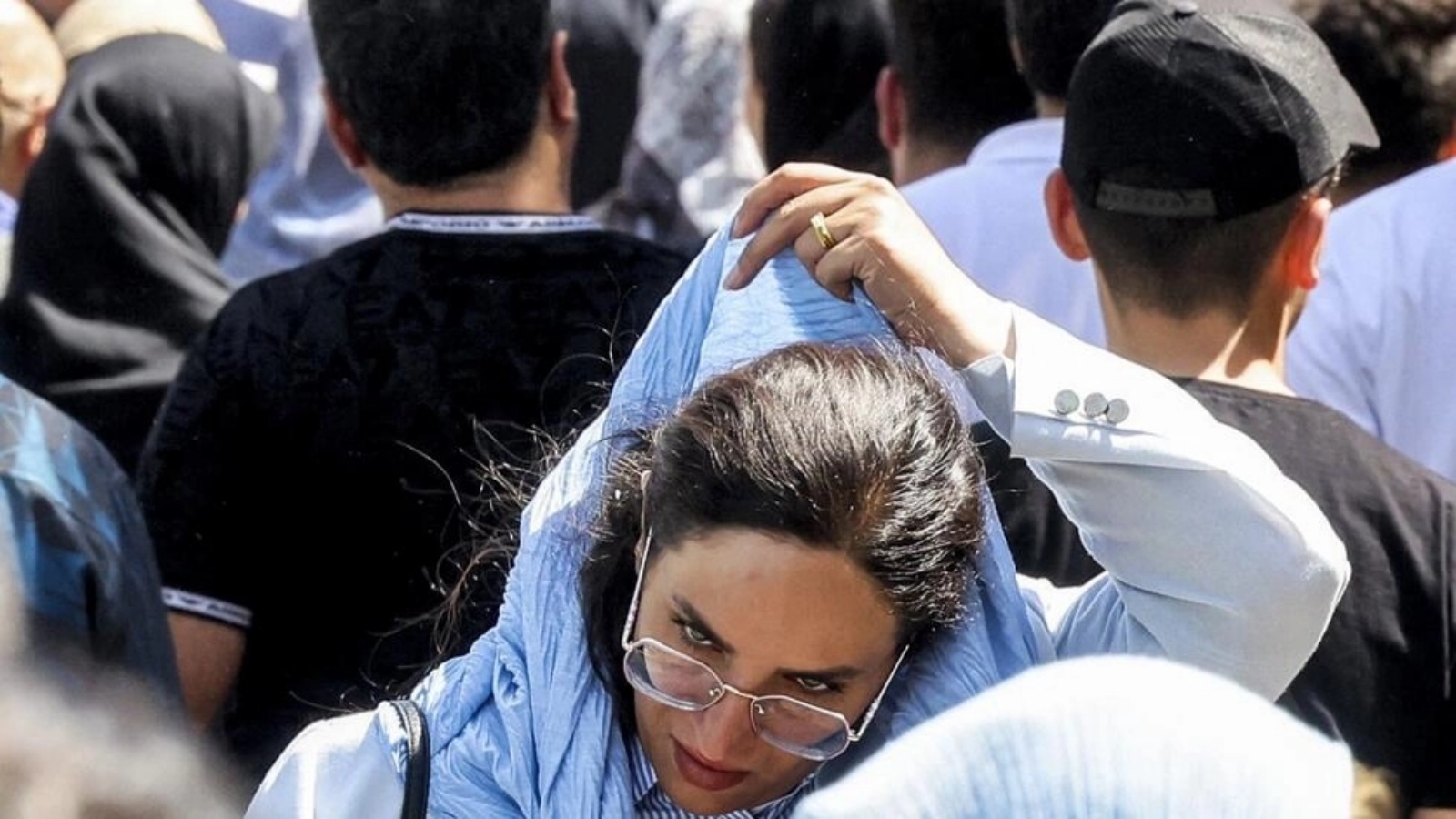 امرأة ترتدي غطاء الرأس أثناء سيرها وسط حشد من الناس خارج البازار الكبير في طهران في 5 أيلول 2023
