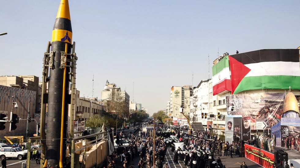 متظاهرون وعناصر من الباسيج يسيرون قرب صاروخ بالستي من الجيل الرابع من طراز خيبر تم عرضه خلال تظاهرة ضد إسرائيل في طهران في 24 نوفمبر 2023