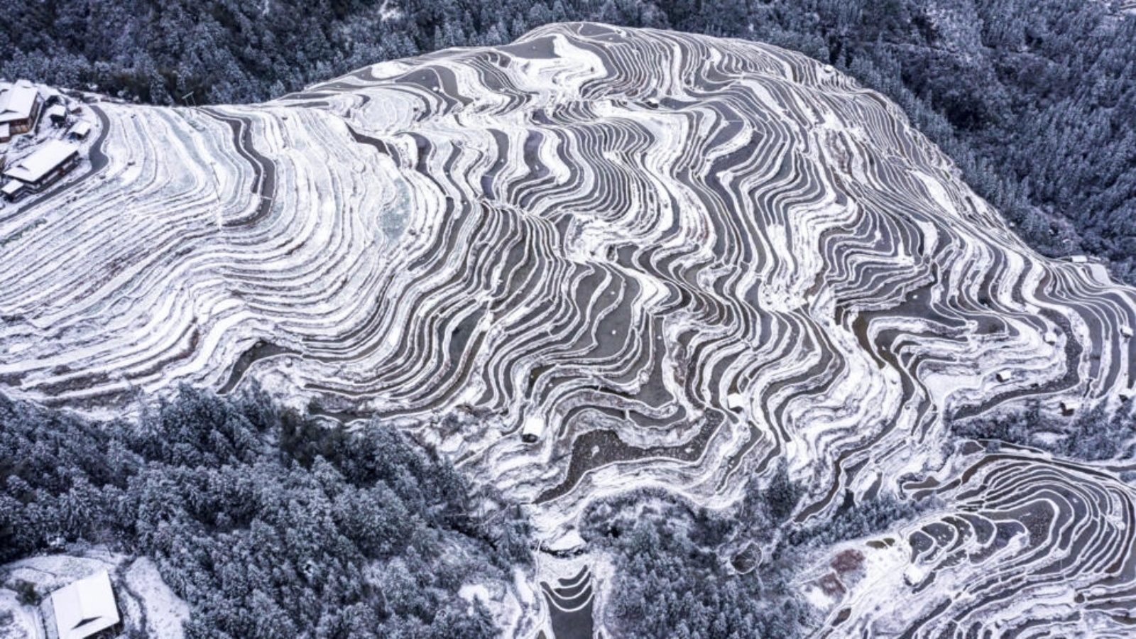لقطة جوية تظهر الحقول والمنازل المغطاة بالثلوج في كونغجيانغ في جنوب غرب الصين في 22 كانون الثاني (يناير) 2024