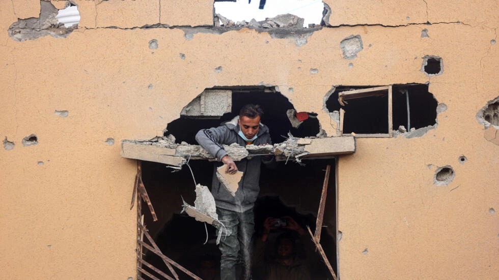 رجل ينظر من نافذة أحد المباني المتضررة في رفح