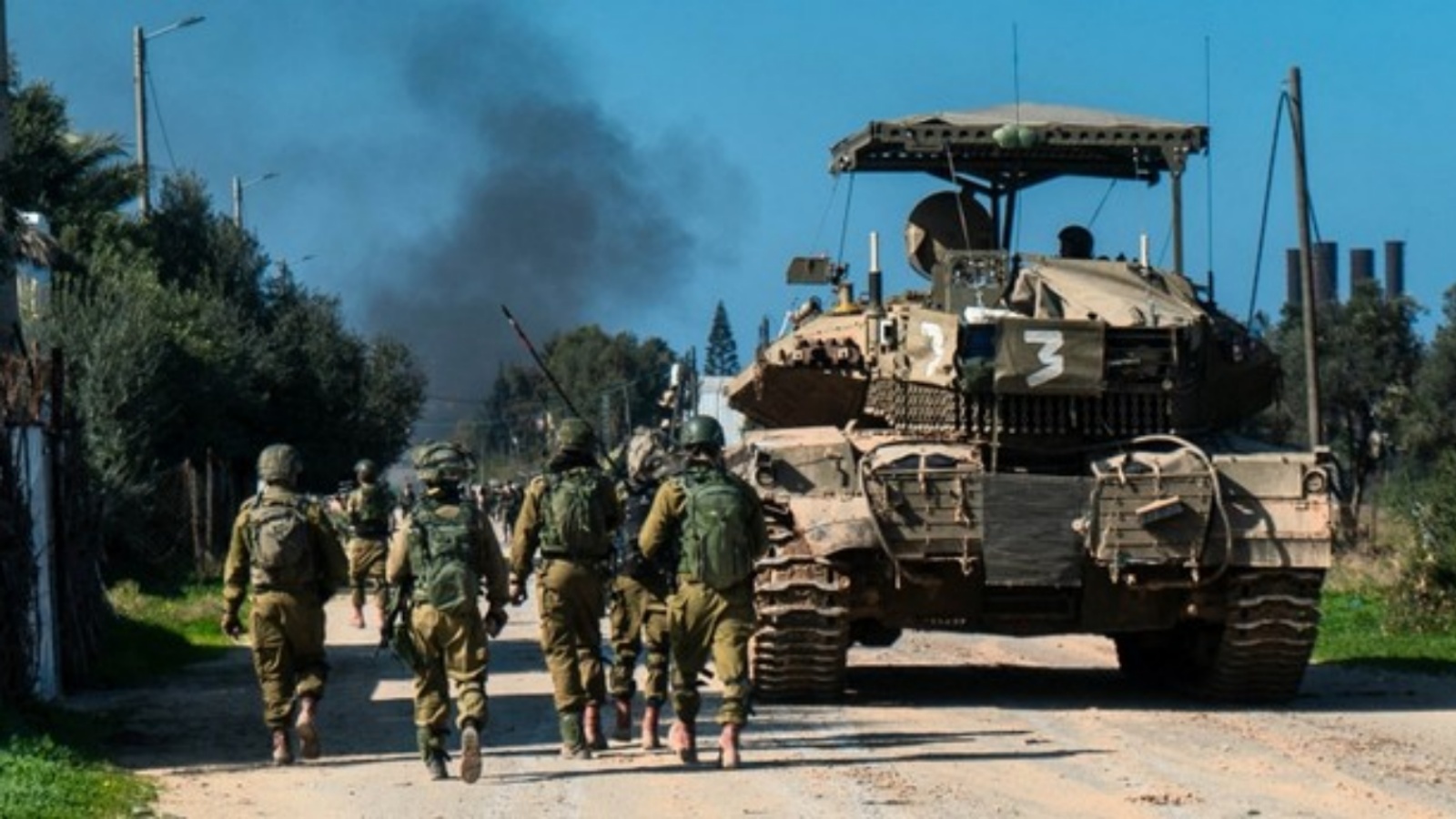 جنود إسرائيليون يسيرون بجانب مركبة عسكرية في قطاع غزة