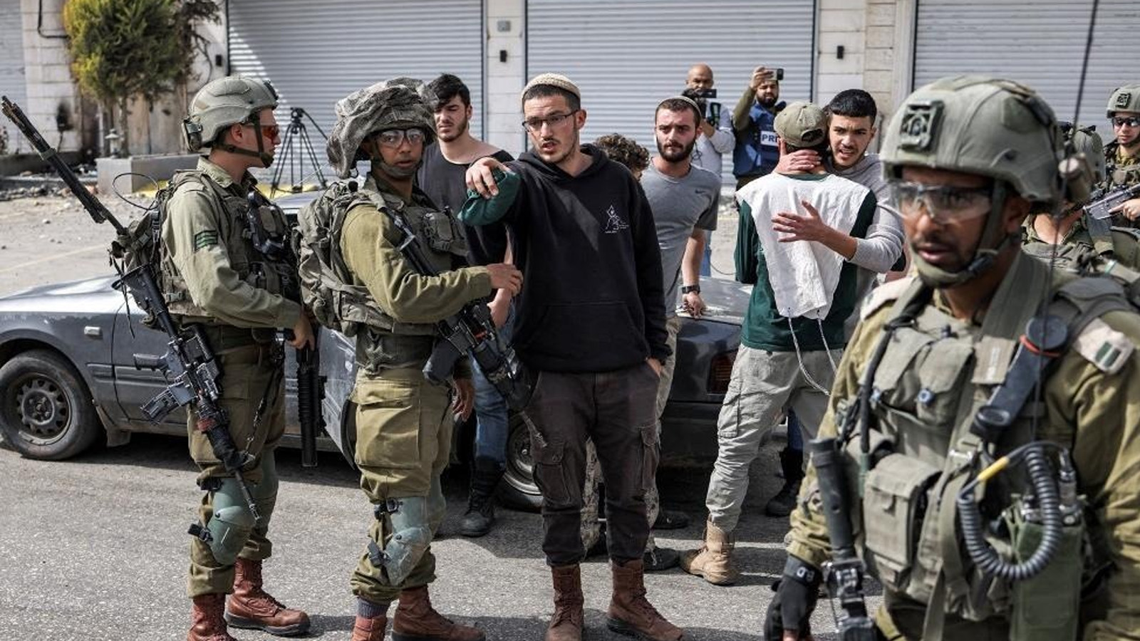 جنود إسرائيليون يتحدثون مع مستوطنين إسرائيليين في بلدة حوارة الفلسطينية بالقرب من نابلس في الضفة الغربية