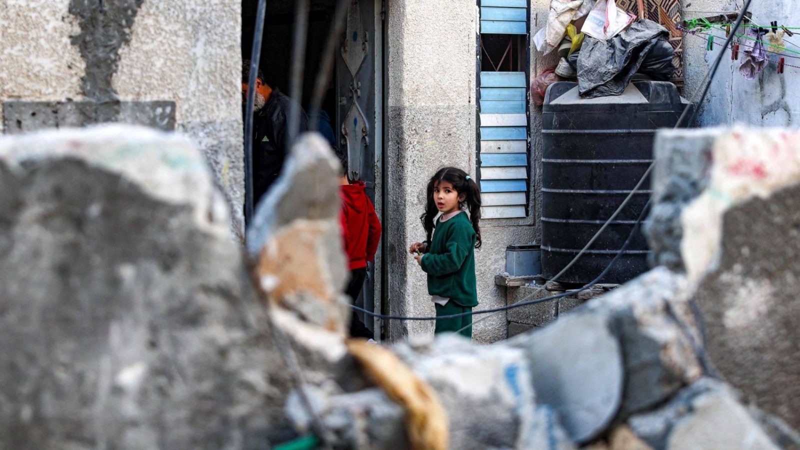 أطفال فلسطينيون يقفون خارج منزلهم قبالة أنقاض مبنى تضرر في القصف الإسرائيلي على رفح في جنوب قطاع غزة 
