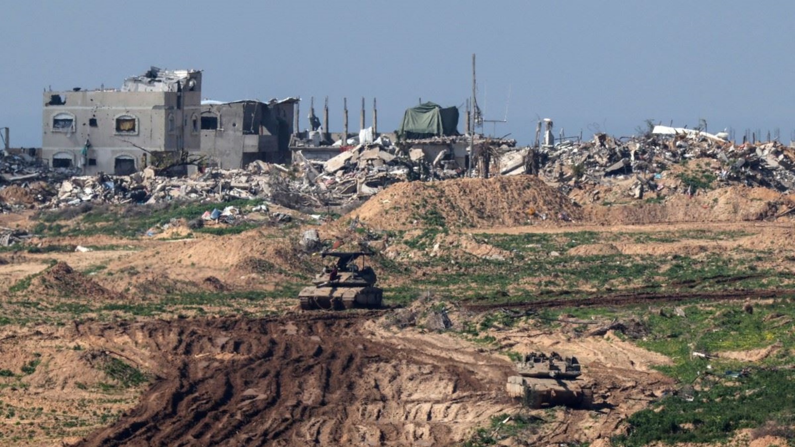دبابات إسرائيلية تمرّ أمام المباني المدمّرة في قطاع غزة