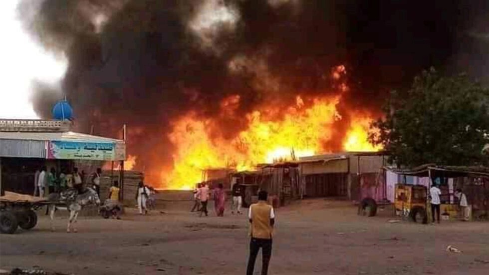 رجل يقف متفرجا بينما تشتعل النيران في منطقة سوق للماشية في الفاشر عاصمة ولاية شمال دارفور السودانية في 1 أيلول/سبتمبر 2023 في أعقاب قصف لقوات الدعم السريع