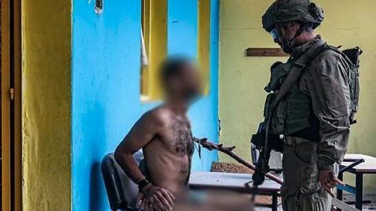 جندي من الجيش الإسرائيلي يستجوب أحد المعتقلين في غزة