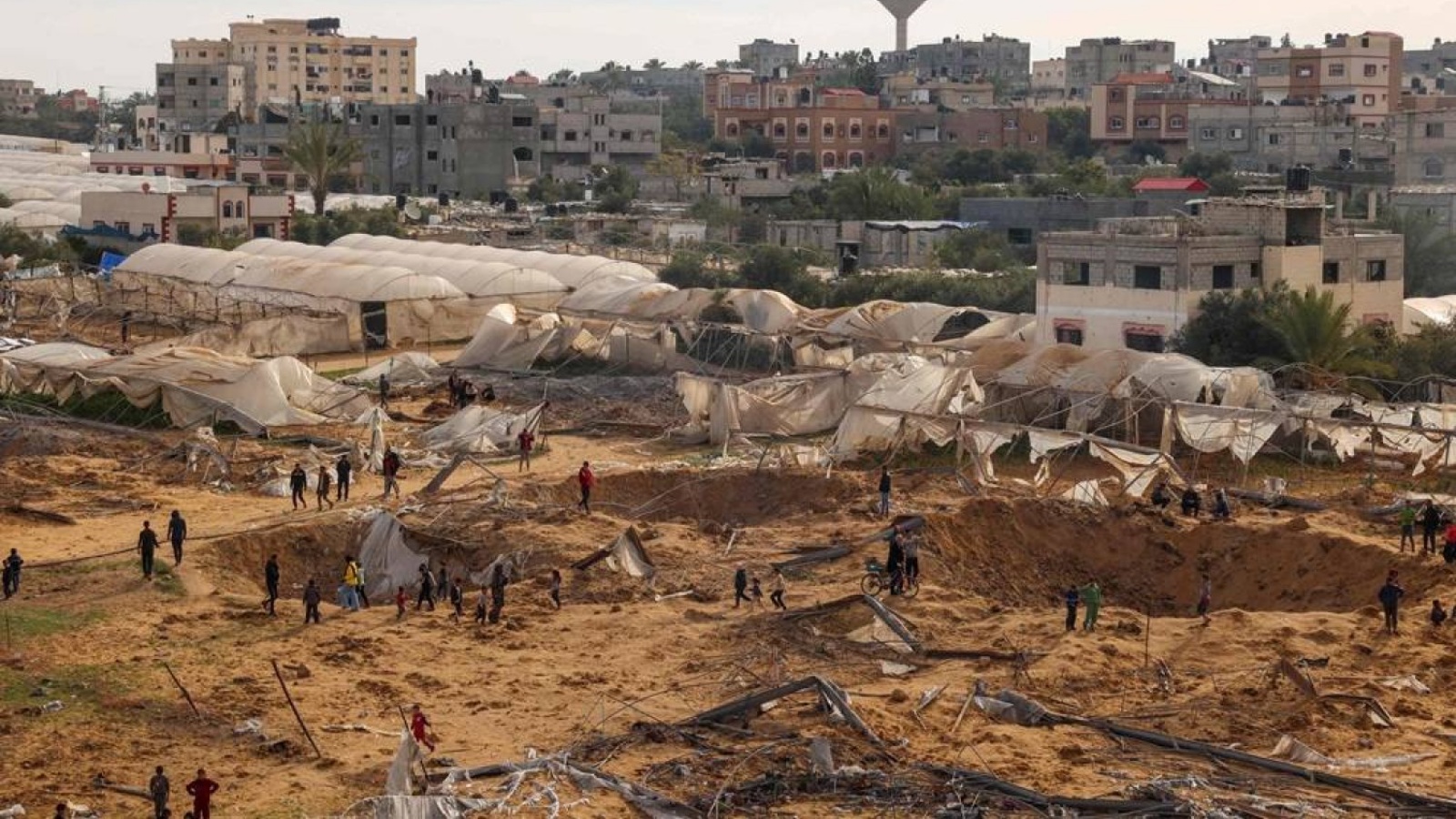 أشخاص يقفون حول الحفر الناجمة عن القصف الإسرائيلي في رفح بجنوب قطاع غزة في 12 شباط (فبراير) 2024، وسط معارك مستمرة بين إسرائيل وحركة حماس المسلحة