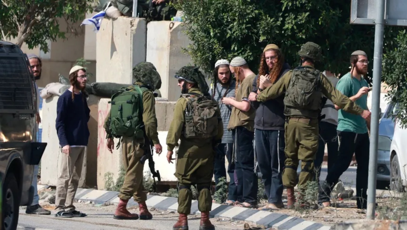 جنود إسرائيليون مع مستوطنين أمام مدخل قرية فلسطينية في الضفة الغربية المحتلة. 2 تشرين الثاني (نوفمبر) 2023 