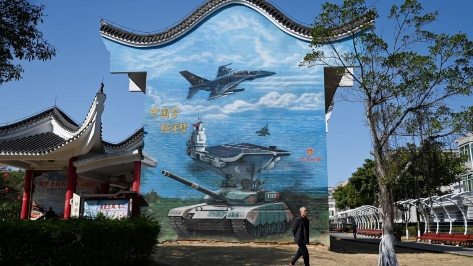 رجل يسير بجوار لوحة جدارية ذات طابع عسكري في حديقة عامة في جزيرة بينغتان، أقرب نقطة في الصين إلى جزيرة تايوان، في مقاطعة فوجيان جنوب شرق الصين في 14 كانون الثاني (يناير) 2024