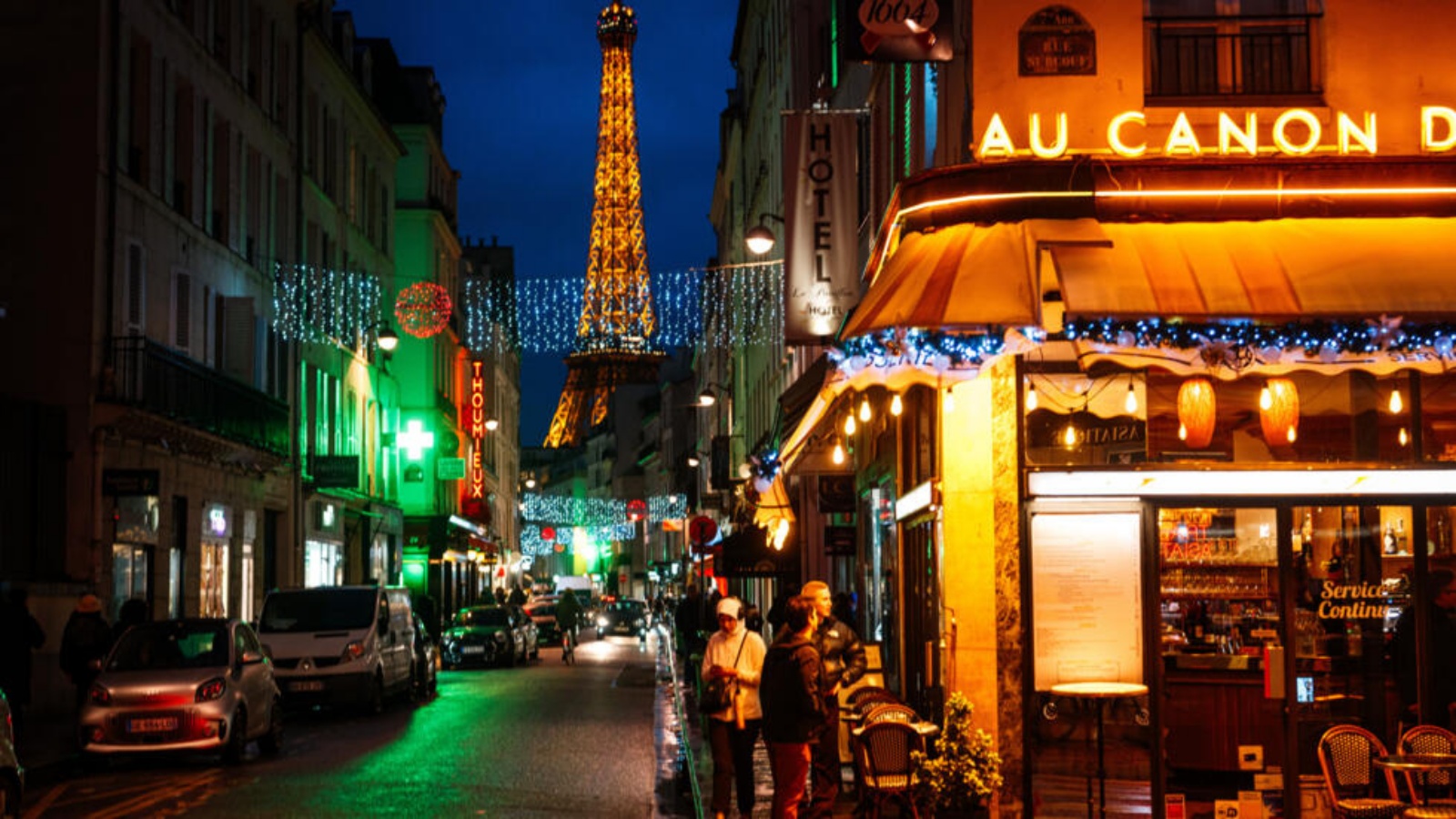 اشخاص يقفون أمام مطعم وخلفهم برج ايفل في باريس في 2 كانون الثاني (يناير) 2024 