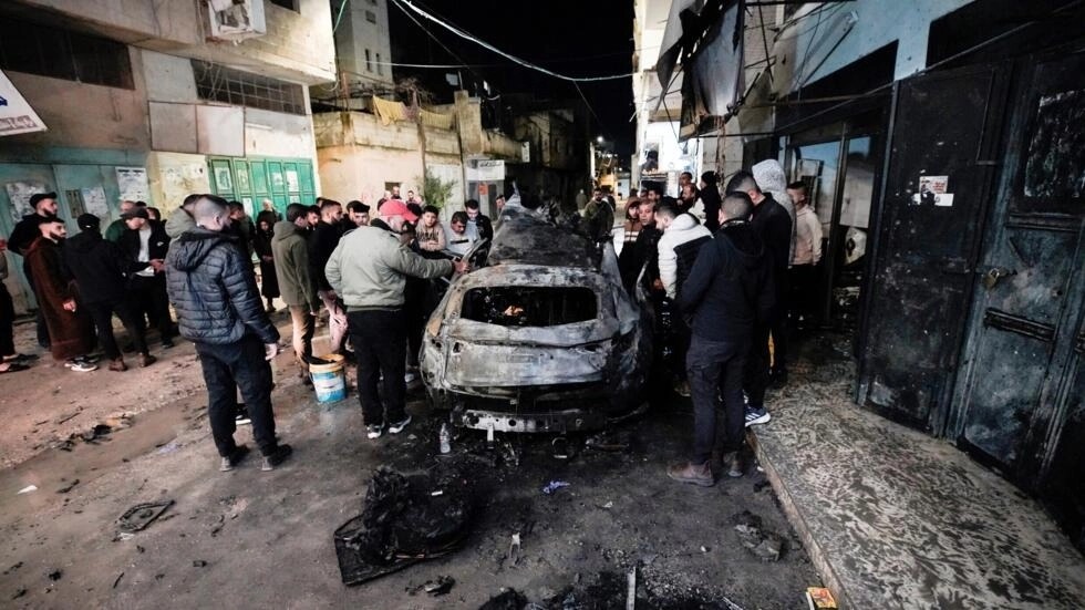 أشخاص يتفقدون سيارة في جنين في 22 شباط/فبراير 2024 قتل فيها فلسطيني وجرح أربعة في ضربة إسرائيلية على سيارة في مخيم جنين للاجئين في الضفة الغربية المحتلة
