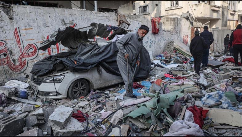 فلسطينيون يحاولون إنقاذ مقتنيات من بين ركام منازل دمرت في قصف إسرائيلي ليلا على مخيم رفح بجنوب قطاع غزة، في 27 شباط/فبراير 2024