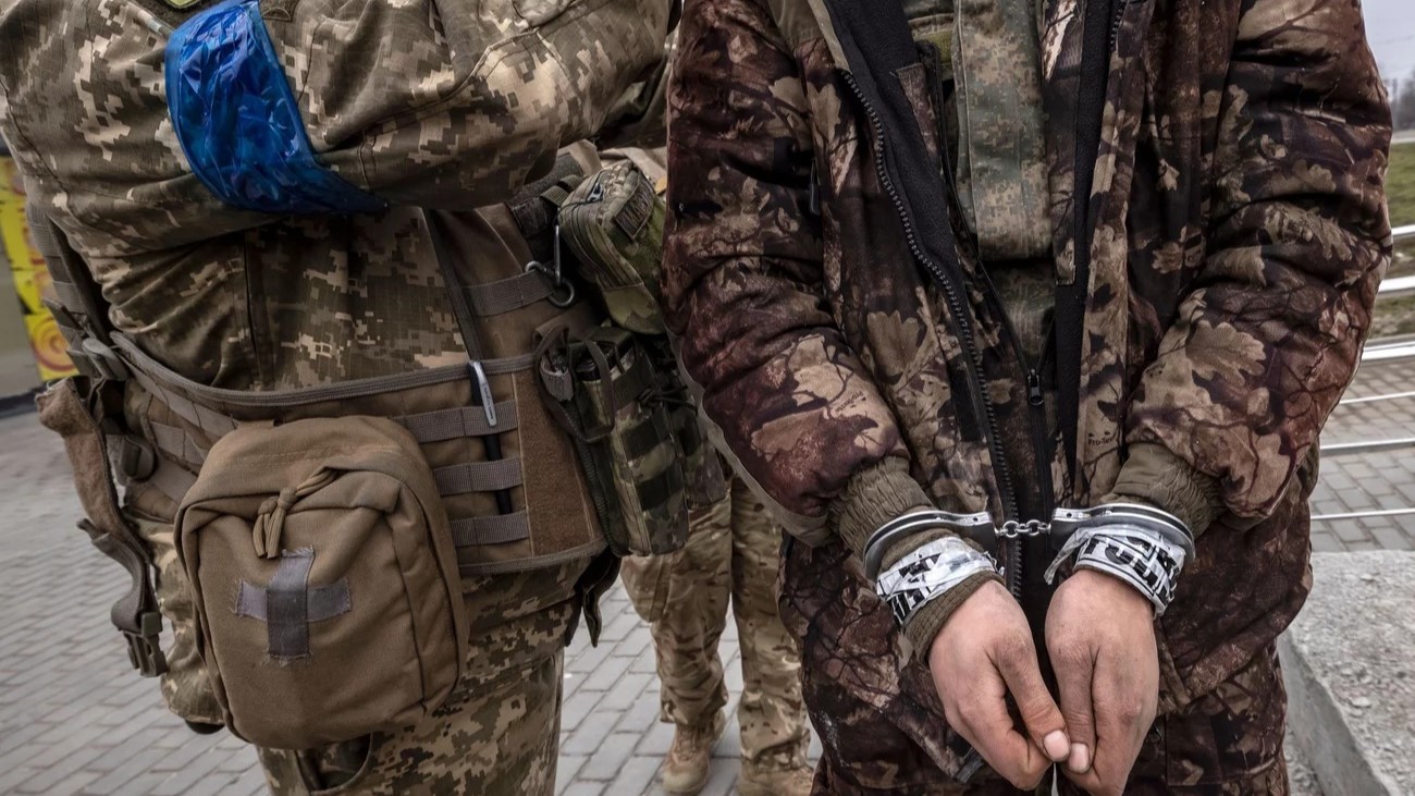 جندي أوكراني يقف أمام جندي روسي مقيد اليدين في خاركيف