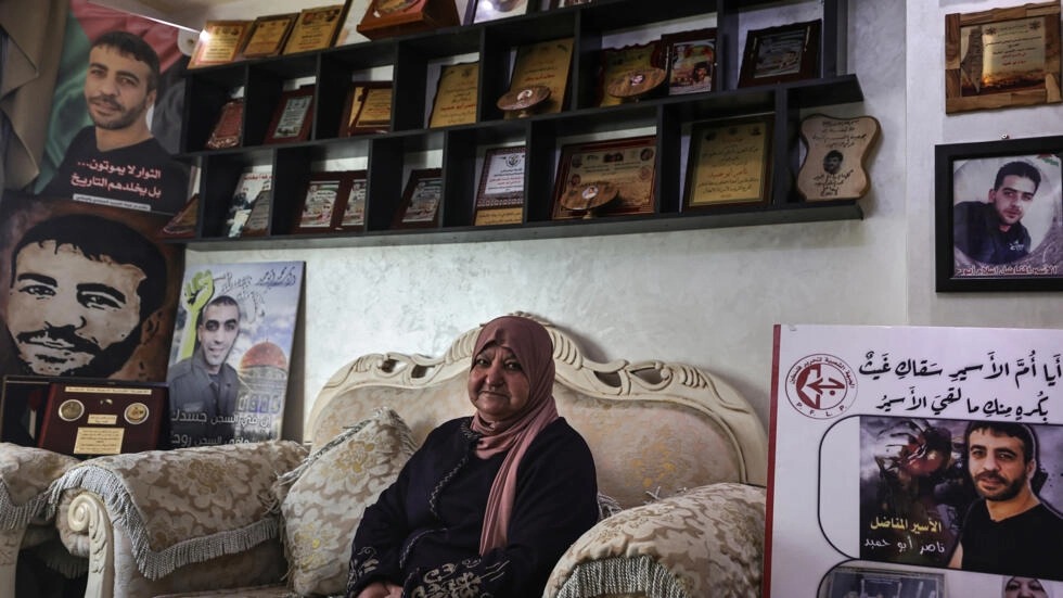 لطيفة أبو حميد (74 عاما) وسط صور أبنائها في منزلها في رام الله بتاريخ 29 شباط/فبراير 2024