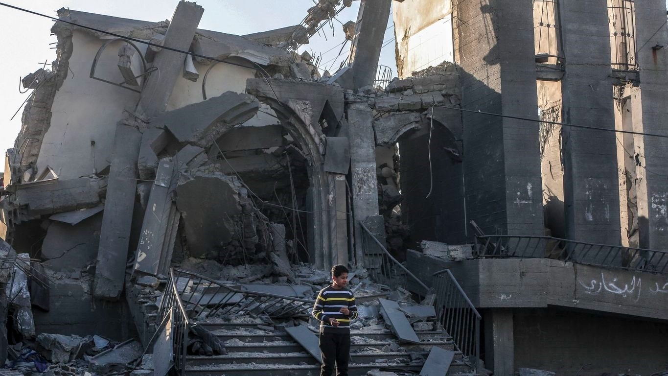 فلسطيني يقف على اطلال مسجد في دير البلح قصفه الطيران الإسرائيلي