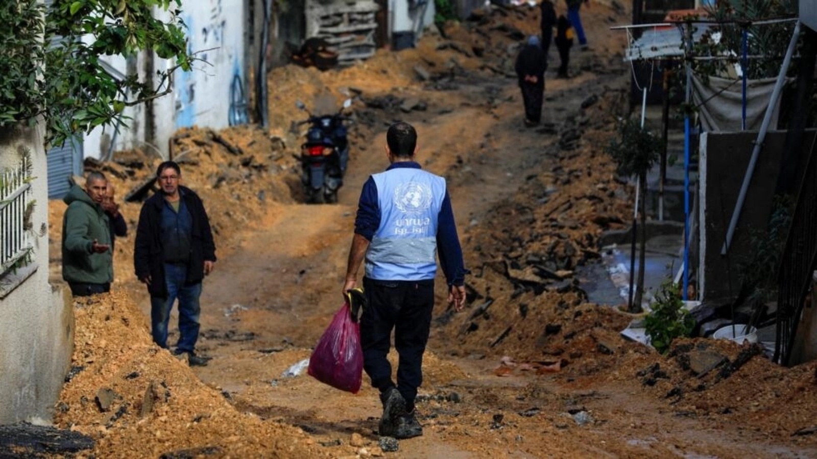 أحد موظفي الأونروا يسير في شارع دمرته القوات الإسرائيلية خلال مداهمة في جنين بالضفة الغربية المحتلة، 29 كانون الثاني (يناير) 2024