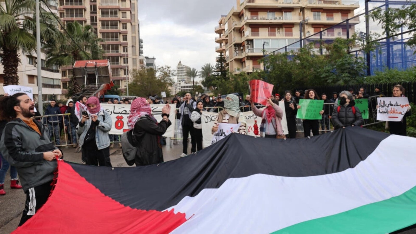 ناشطون يحملون علمًا فلسطينيًا ويقطعون الطريق المؤدي إلى السفارة المصرية في العاصمة اللبنانية بيروت احتجاجًا على إغلاق معبر رفح بين مصر وقطاع غزة، في 19 شباط (فبراير) 2024 