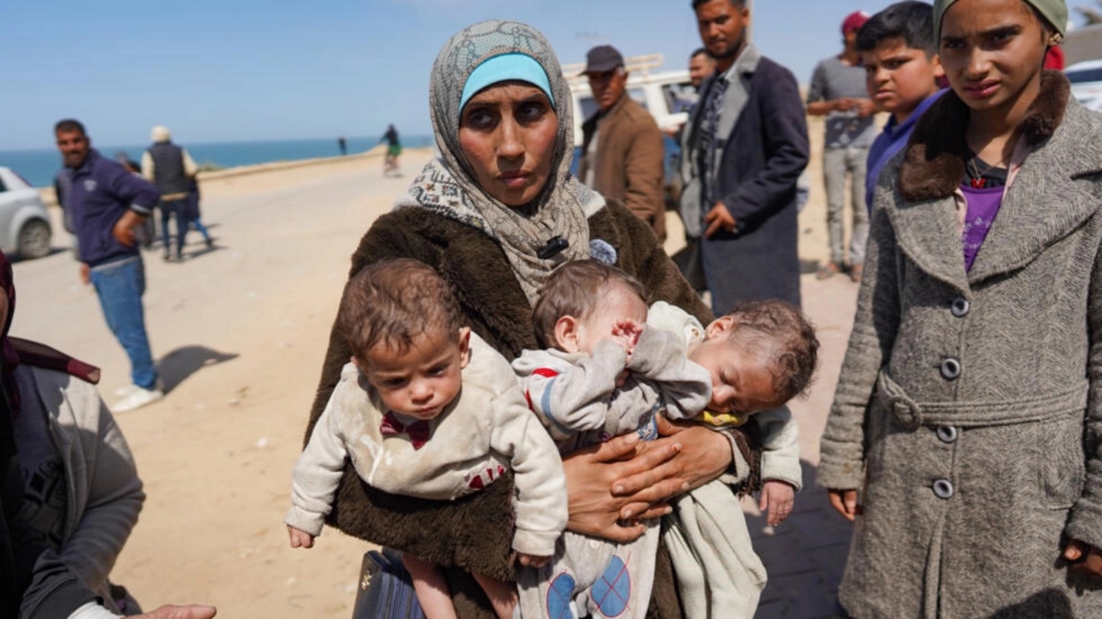 امرأة تحمل ثلاثة أطفال عند وصولها إلى وسط قطاع غزة بعد فرارها من مجمع الشفاءالطبي الذي تحاصره الدبابات في مدينة غزة، في 21 آذار (مارس) 2024 