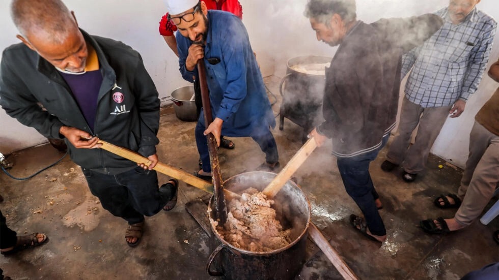 متطوعون يحضّرون حصصاً من طبق البازين الليبي التقليدي في تاجوراء بشرق العاصمة الليبية طرابلس في 13 آذار/مارس 2024