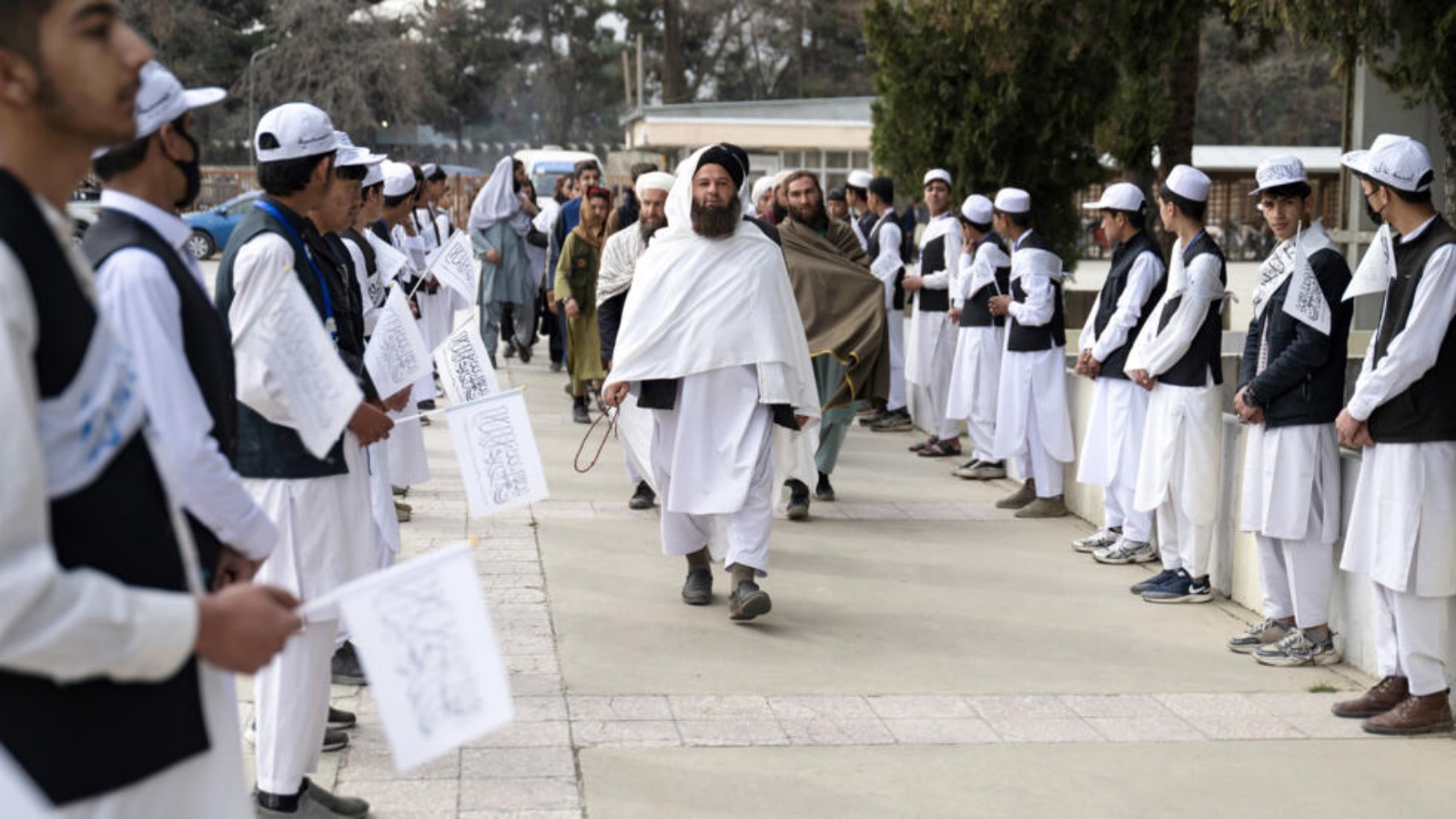 تلاميذ أفغان يحملون أعلام طالبان خلال استقبال مسؤولين محليين في حفل بمناسبة بدء الموسم الدراسي في مدرسة 