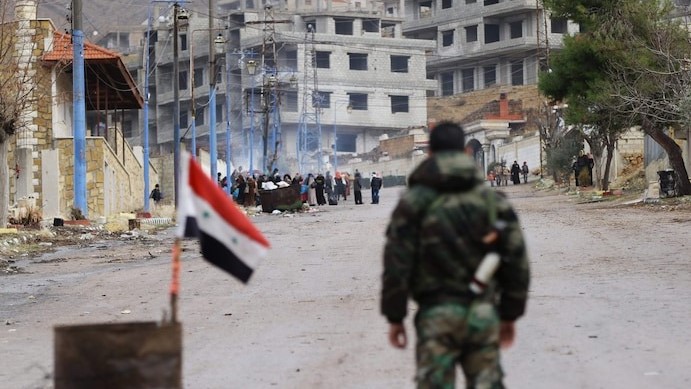 جندي تابع للنظام السوري عند مدخل بلدة مضايا المحاصرة، بينما ينتظر السكان وصول قافلة مساعدات في 14 يناير 2016