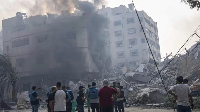 فلسطينيون أمام مبنى أصابته الغارات الإسرائيلية في غزة